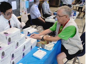 Pharmacist Jaydon Tsui checks the blood sugar of Mel Douglas at a health fair hosted by Canadian Diabetes Association in Regina.