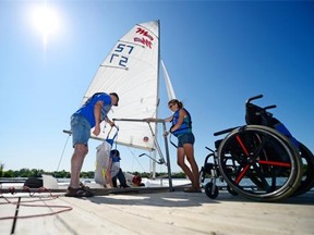 Greg McDonald, left, and Heather Robinson, right, use a Hoyer lift to assist Charlene Eger from her wheelchair to sailboat on the dock as part of the Wind on my Wings Sailing Club on Wascana Lake in Regina on Saturday.