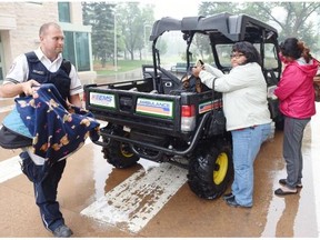 REGINA, SK: JUNE 29, 2015 --  Paramedic, Donovan Ljubic takes Saskatchewan forest fire evacuees Camari Whitecap 5 months and  Marlene McKay (C) and Camellia Whitecap (R) from the Red Earth First Nation to the University of Regina residence towers on June 30, 2015. Patrons were given meals by university catering staff throughout the day. Evacuees with health problems such as respiratory issues are being housed in the residence towers. (DON HEALY/Regina, Leader-Post) (Story by Paige Kreutzwieser) (NEWS)