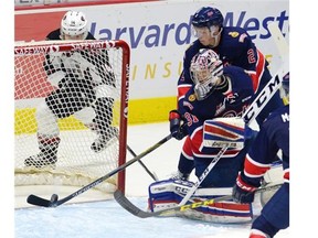 Pats goal tender Tyler Brown watches as teammate Sergey Zborovskiy keeps the puck from entering the net during WHL action at the Brandt Centre Friday Oct. 9, 2015.