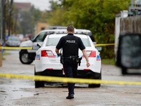 A Regina Police Services member walks near a crime scene in the 1600 block of Ottawa St. in Regina, Sask. on Saturday Aug. 22, 2015.