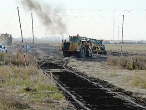 A pair of earthmoving scrapers work just south of the Trans-Canada Highway and Pilot Butte turnoff just east of Regina in Wednesday.