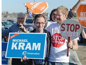 Robert Thomas, left, and Sean Tucker, right, hold signs during a Conservative Party campaign stop at the Regina International Airport in Regina, Sask. on Sunday Oct. 18, 2015. The pair are colleagues who both work at the University of Regina. (Michael Bell/Regina Leader-Post)