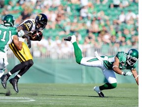 Saskatchewan Roughriders defensive back Geoff Tisdale (#21) tries to bring down Hamilton Tiger-Cats wide receiver Terrence Toliver (#80) at Mosaic Stadium in Regina on Sunday.