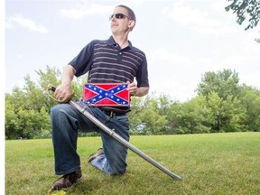 Dale Pippin poses for a photograph with a replica U.S. Civil War sabre and Confederate flag plate.