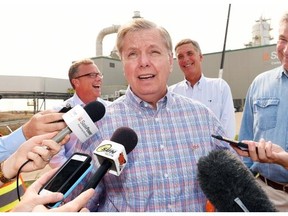 U.S. Senator Lindsey Graham (C) speaks while flanked by Premier Brad Wall (L) and Congressman Tom Rice and U.S. Senator Sheldon Whitehouse (R) before a tour of the Boundary Dam Carbon Capture plant just outside of Estevan on August 26, 2015.