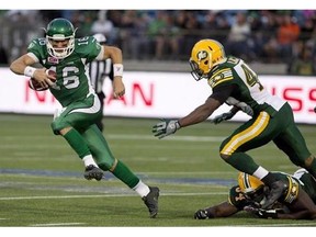 Saskatchewan Roughriders' Brett Smith (16) dodges the tackle from Edmonton Eskimos' Ryan Hinds (34) and Deon Lacey (40) during second half CFL pre-season action in Fort McMurray, Alta., on Saturday June 13, 2015. Smith will make his first CFL start Friday night when the Roughriders visit the Eskimos.