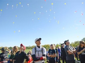 Jim Syrgiannis, center, looks up as balloons are released at the Terry Fox Run which began at the T.C. Douglas building in Regina, Sask. on Sunday Sep. 20, 2015.