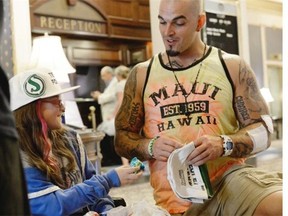 Tiffany McLennan, left, gives Toronto Argonauts' Ricky Foley a bracelet she made for the former Riders defensive end.