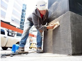 Dan Tokarski with Van Alstine Project Management cleans column bases at Conexus Plaza on Hamilton Street in downtown Regina on Friday.