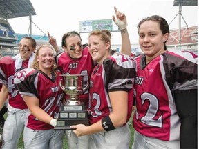 Regina Riot Ariel Blondeau, from left, Shelby Moran, Katie Rogal, Carmen Agar, and Aimee Kowalski celebrate with the WWCFL championship trophy at Investors Group Field in Winnipeg.