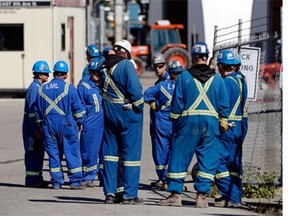 Workers at the Co-op Refinery Complex stand near the outside fence as emergency crews work in Regina on Thursday.