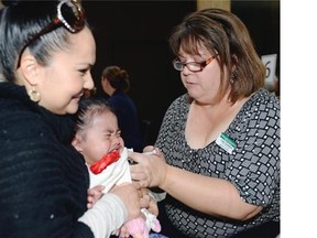 Two year old Kawai Lafontaine cringes while hanging on to mom Rosanna Lafontaine as public health nurse Lana Caufield gives her a flu shot as the Regina Qu´Appelle Health Region´s annual influenza immunization season kicks off October 19, 2015.