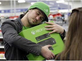 Emanuel Jumatate, from Chicago, hugs his new Xbox One after he purchased it at a Best Buy on Friday, Nov. 22, 2013, in Evanston, Ill.