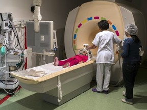 Technicians prepare a young girl for an MRI scan.