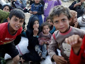 Syrian refugees wait after crossing into Turkey.