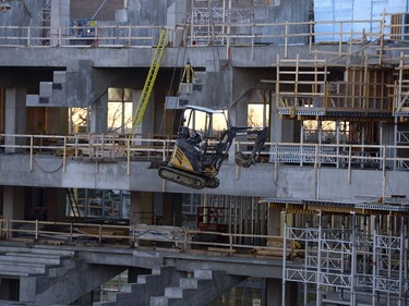 Crane operators move construction equipment around inside the stadium.