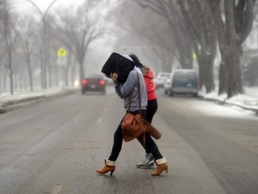 Pedestrians make their way across Victoria Avenue at Montreal Street against high winds in Regina, SK on November 18, 2015.