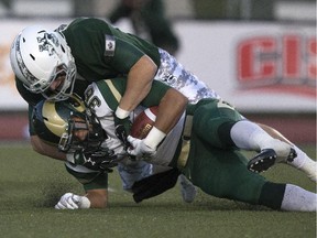 Atlee Simon of the University of Regina Rams, white top, is brought down by Tristian Koronkiewicz of the University of Saskatchewan Huskies during CIS action at Griffiths Stadium, Friday, September 18, 2015.