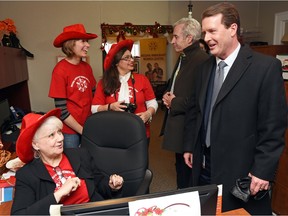 Theresa Norlander (L) with the Regina Immigrant Women Centre talks with Mayor Michael Fougere (R) at the  centre's annual Christmas open house on Dec. 15, 2015.  In the background is Minister of Parks, Culture and Sport Mark Doherty speaking with centre staff.