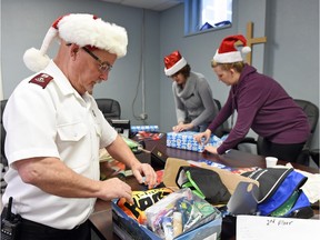 Maj. Glenn Patey, a chaplain with the Salvation Army, loads up shoe boxes with gifts wrapped by volunteers Lisa Bisgaard (L) and Ashleigh Woytuik for the men at Waterston Centre Men's Shelter.