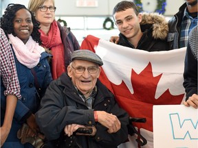 Usama Ahmad (right with flag), a 20-year-old Syrian refugee from Damascus with 98-year-old Jack Boan (seated) Professor Emeritus of Economics from the University of Regina and fellow university students and friends after arriving at the Regina airport. Ahmad is the first U of R-funded Syrian refugee to arrive.