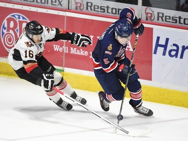 Calgary Hitmen Dawson Martin, left, fights for the loose puck with Regina Pats Colby Williams in WHL action at the Brandt Centre in Regina on Wednesday.