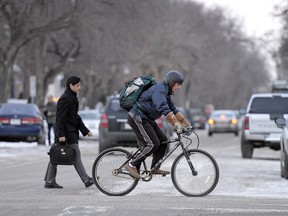 A cyclist on 13th Avenue in afternoon commuting traffic in Regina.