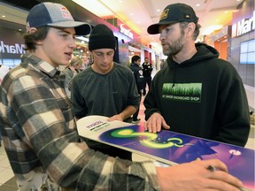 Mark McMorris, left, and his brother Craig, centre, sign a snowboard for Brian Buchanan on Tuesday morning at the Southland Mall.