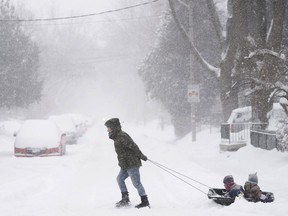 A woman pulls children in a sled during a storm with strong winds and heavy snow, Monday, Feb. 2, 2015, in Toronto. (AP Photo/The Canadian Press, Darren Calabrese)