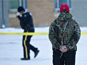 A man holds a rosary as police investigate the scene of the shootings at the community school in La Loche.