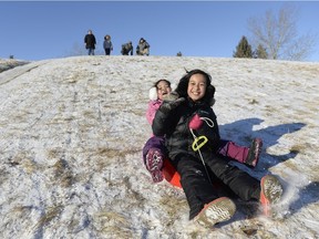 Ayn Borja, far right, and Julia Cuenco, right, toboggan in the shallow snow while their families look on at A.E. Wilson Park in Regina, Sask. on Saturday January 2, 2016. Michael Bell/Regina Leader-Post