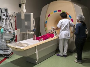 A nurse prepares a young girl for an MRI test.