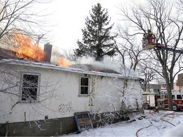 Regina Fire and Protective Services members prepare to douse a house fire from above at 1457 Rae St. in Regina, Sask. on Saturday January 23, 2016.