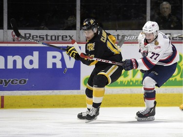 Regina Pats forward Adam Brooks (77) and Brandon Wheat Kings defence Kale Clague (10) battle for the puck while goalie Jordan Papirny (33) skates back to his net during a game at the Brandt Centre in Regina, Sask. on Sunday January 24, 2016.