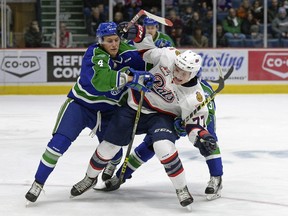 Regina Pats centre Adam Brooks, right, battles with Swift Current Broncos defenceman Kade Jensen, left, during Friday's WHL game at the Brandt Centre.