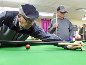 Robert Brann (L) and Oscar Rivera (R) discuss the impact of a national drug plan when they take a break from their pool game at the Regina Senior Citizens Centre in Regina.