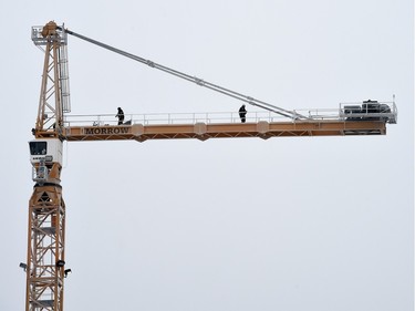 Two construction workers walk along a hi-rise crane during a foggy morning at the site of the new Mosaic Stadium in Regina on January 20, 2016.