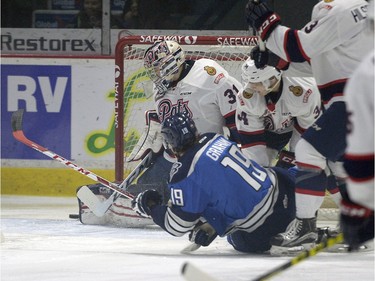 Pats goaltender Tyler Brown covers the net as Blades' Ryan Graham tries to put on in the corner during WHL action between the Regina Pats and Saskatoon Blades in Regina.