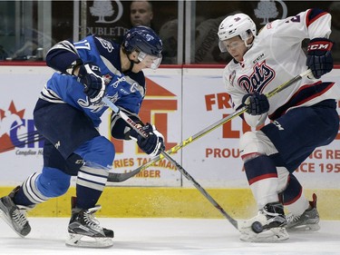 Pats' Sergey Zbrorovskiy and Blades' Nick Zajak battle for the puck during WHL action between the Regina Pats and Saskatoon Blades in Regina.