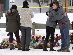 People come to lay a wreath and flowers at a roadside memorial in front of the La Loche Community School on Jan. 27.