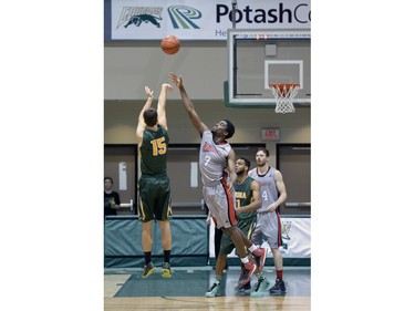 Cougars forward Will Tallman launches a successful three-pointer while Wesmen forward Jelane Pryce attempts to block him during a playoff game against the Wesmen at the University of Regina on Saturday Feb. 27, 2016.