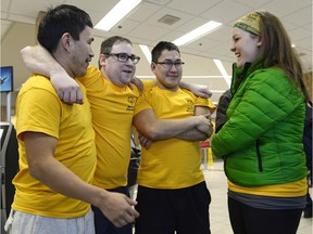 Floor hockey players Peter Algona, Tyler Haddad and Allen Algona, left, and assistant coach Abigail Frasz, right, share a moment of excitement before the team checks in at the Regina International Airport on Sunday. The team is headed to the Special Olympics Canada Winter Games being held in Corner Brook, N.L.