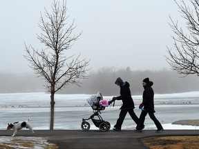 Carolyn Martin (C) with her mother, Lisa Tabin (R) and nine-month-old daughter Hatley Martin along with her dog, Mr. Darcy during a misty fog in Wascana Park.