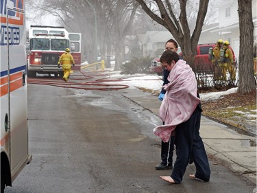 EMS help a barefoot boy cross an icy street to a waiting ambulance during a house fire at 117 Milne Street in Regina on February 18, 2016.