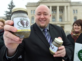 Terry Bell, NDP candidate for Regina Walsh Acres, in front of the Saskatchewan Legislative building with jars of dirt representing what the NDP calls an inflated price for land in the Global Transportation Hub.