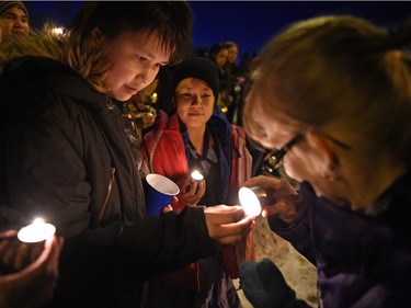 Krystal Lavallee (R) lights up Marizah Wahpoosewyan (L) during a vigil being held to draw attention to violence in North Central and elsewhere in Regina.  Core area community members listened to elders speak and sing honour songs and took part in a sweet grass ceremony and made a public call to end violence.