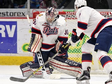Regina Pats netminder Tyler Brown and teammate Sergey Zborovskiy scramble for the puck during WHL hockey action against the Red Deer Rebels at the Brandt Centre in Regina on February 29, 2016.