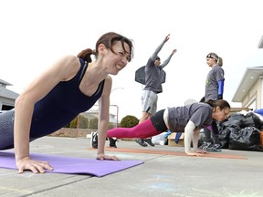 Tiffany Hersak, left, strains while doing a burpee at a home in Westhill Neighbourhood in northwest Regina on Saturday Feb. 27, 2016. Hersak is part of Winter Warriors, a program of Conviction Fitness, that helped collect over 2,000 items for the Saskatchewan Association for Community Living. The participants agreed to do 15 burpees for every donated item.