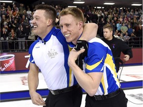 Alberta lead Ben Hebert, left, celebrates with third Marc Kennedy after helping the Kevin Koe-skipped Alberta team win the Brier in Ottawa on Sunday.
